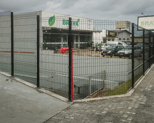Gradil preto instalado no perímetro de uma empresa, com portão e fechamento da área externa.