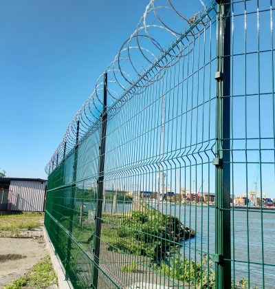 Gradil verde com concertina instalado pela Telas Prime em área industrial próxima ao porto