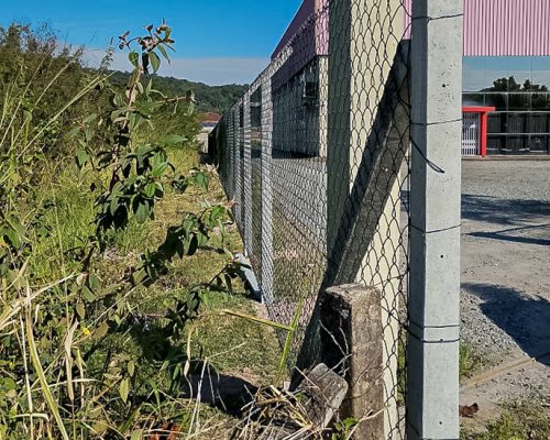 Alambrado galvanizado com mourões de concreto instalado no perímetro de uma empresa.