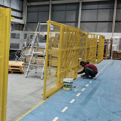 Cercamento em gradil metálico amarelo instalado em área industrial para proteção e isolamento de máquinas.